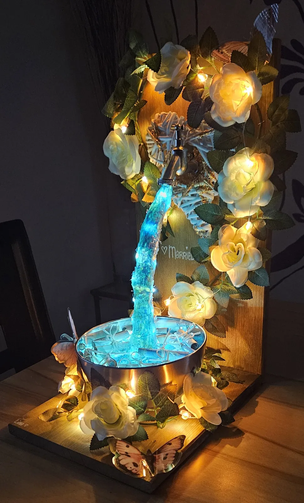 Beleuchteter Geldgeschenk-Brunnen mit Rosen, Ansicht mit Schmetterling
